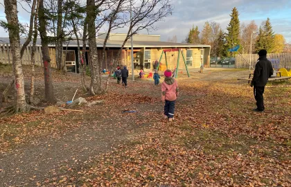 Workinnmarka barnehage uteområde med store trær og løv på bakken en sen høstdag