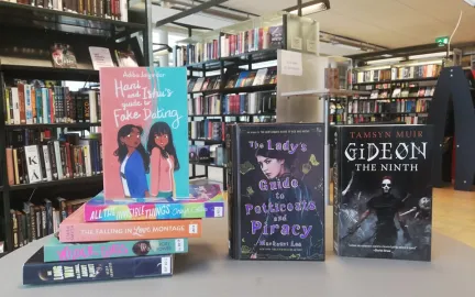 Tre b&oslash;ker oppstilt med fronten mot kamera, fire b&oslash;ker ligger p&aring; bordet ved siden. Foto.