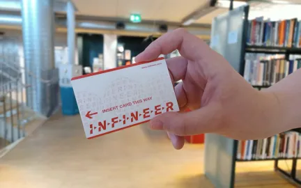 Kopikort utgår Et hvitt og oransje kort holdes av en hånd. I bakgrunnen står det bokhyller. Foto.