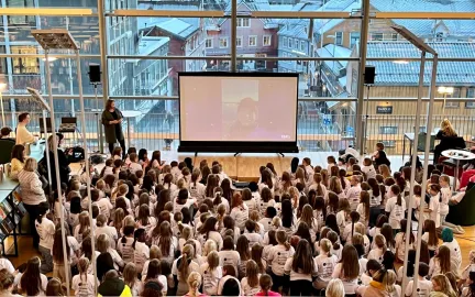 En stor gruppe jenter sitter på plan 2 i biblioteket med ryggen vendt mot kameraet. Foto. Girl Tech Fest 2022