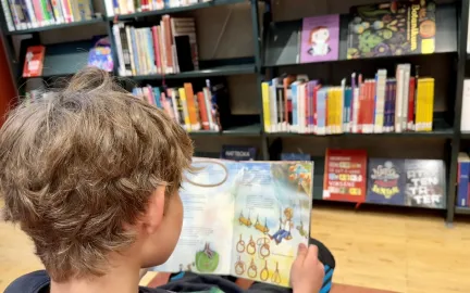 Barn leser bok på bibliotek